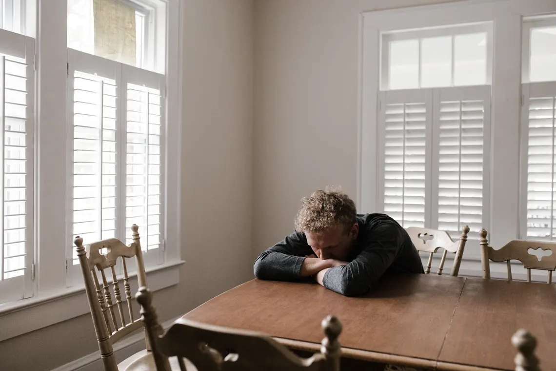 A person sitting alone with their head lowered